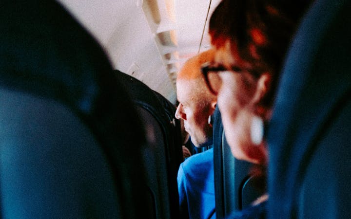 A view inside an airplane cabin showing passengers seated and looking forward.