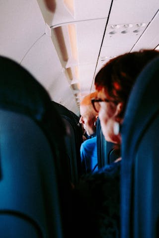 A view inside an airplane cabin showing passengers seated and looking forward.