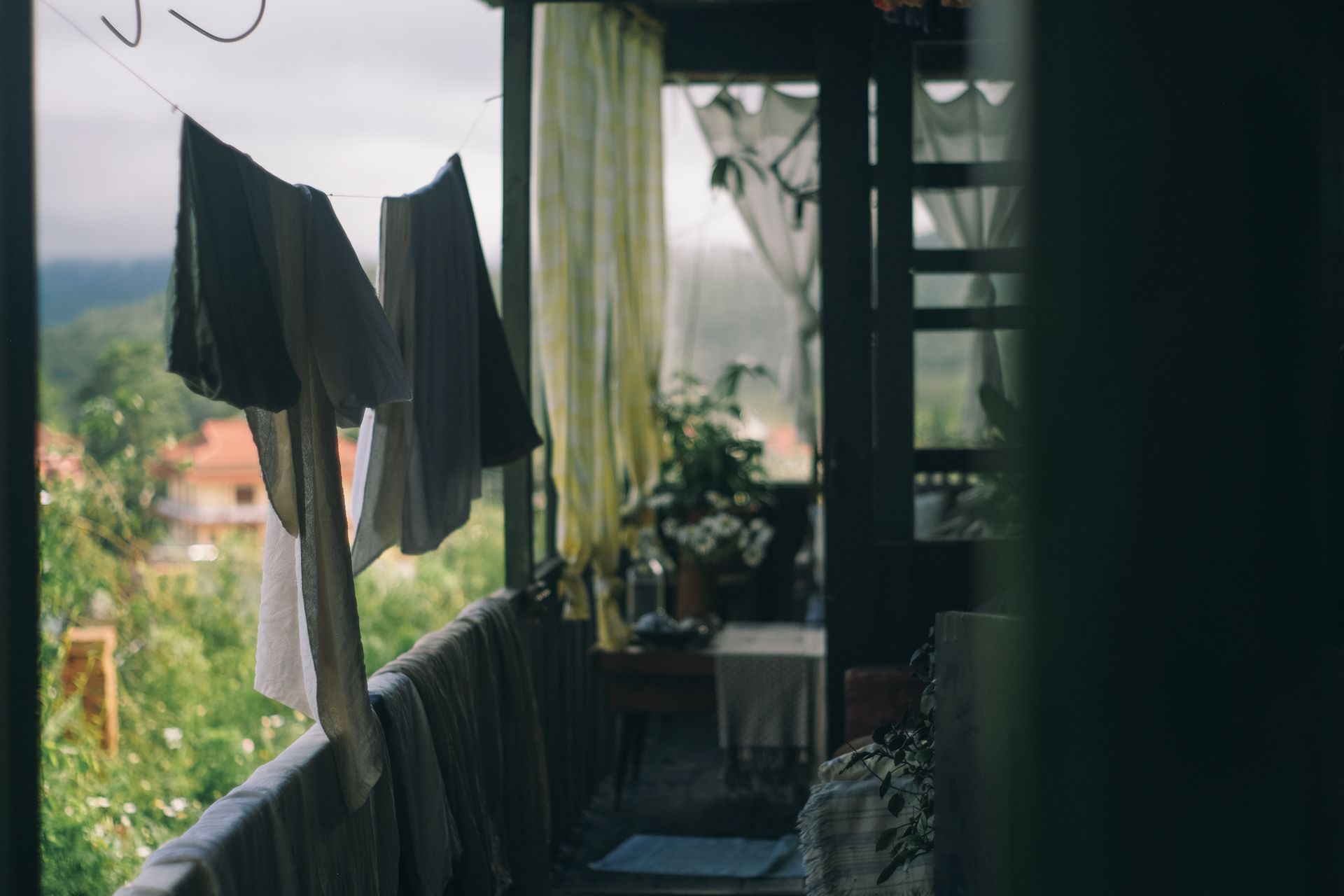 A cozy balcony with clothesline and hanging laundry overlooking lush greenery, creating a serene home vibe.