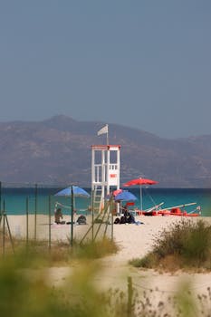 Relaxing beach scene with lifeguard tower and umbrellas on Poetto Beach, Sardinia.