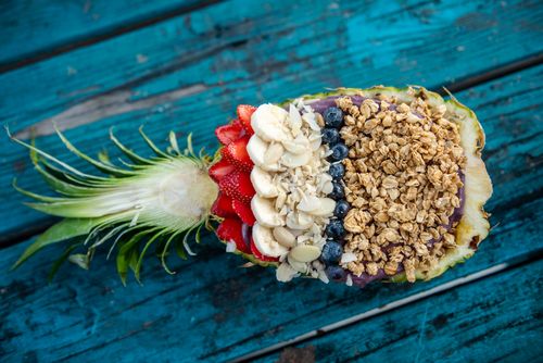 Free Healthy fruit and granola bowl in a pineapple shell on turquoise rustic table, perfect for a nutritious breakfast. Stock Photo