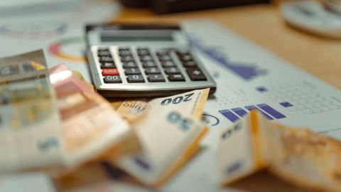 Euro banknotes and calculator on financial documents, focusing on business budget planning.