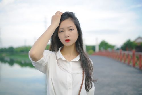Free Portrait of a young woman outdoors in a white shirt, showcasing a relaxed summer vibe. Stock Photo