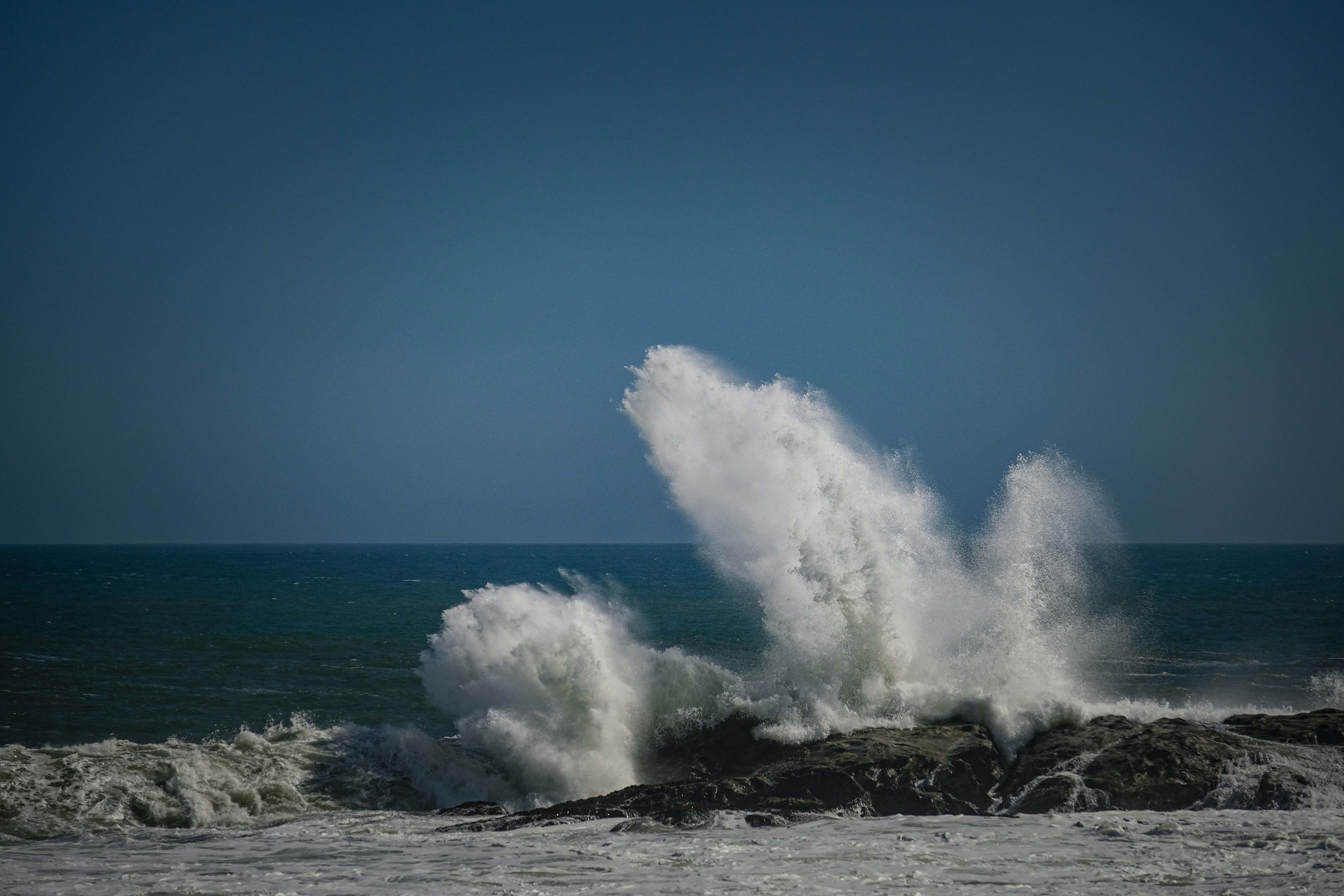 A large wave crashing into the rocks at the beach · Free Stock Photo