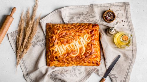 Free Golden brown homemade pie with decorative crust on linen fabric surrounded by spices and oil. Stock Photo