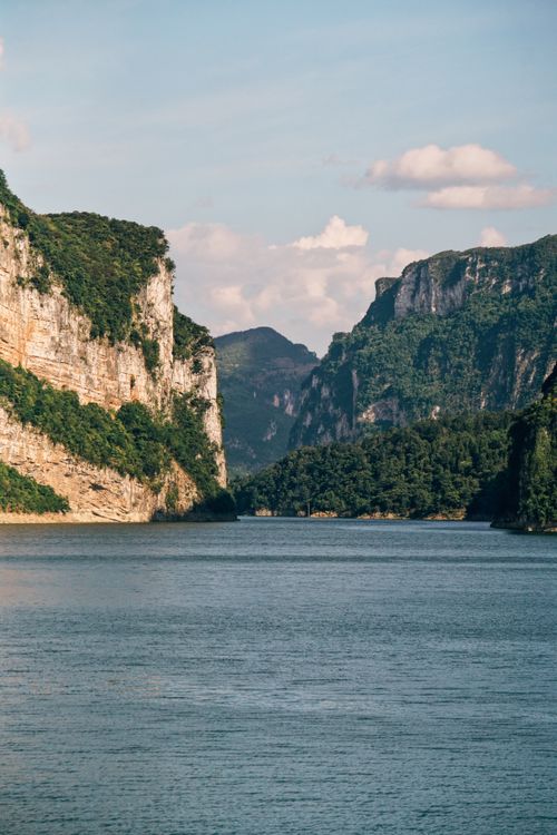 Free A stunning view of a tranquil river winding between towering cliffs under a clear blue sky. Stock Photo