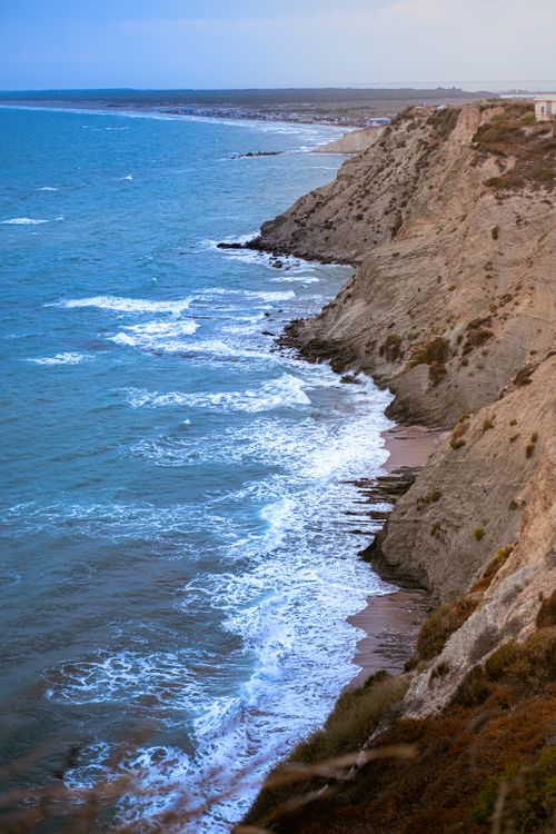 Free A breathtaking view of rocky cliffs and ocean waves crashing ashore, perfect for travel inspiration. Stock Photo