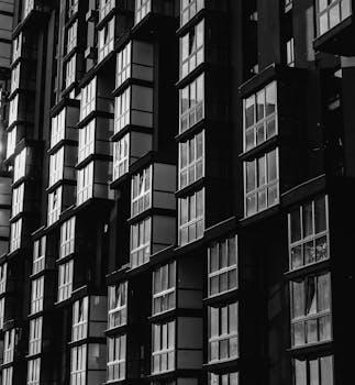 一张现代建筑立面的戏剧性黑白照片，窗户带有几何图案