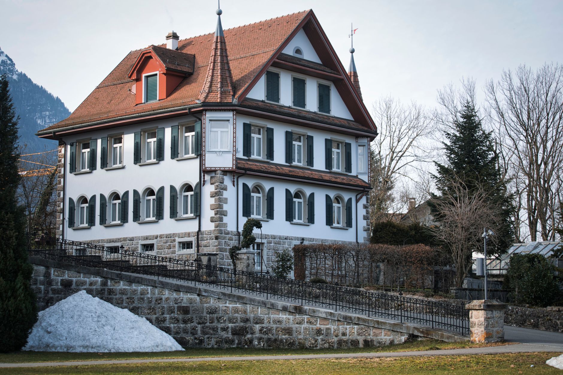 A gable-roofed house with a red roof covered in snow, illustrating uneven snow accumulation across a pitched roof