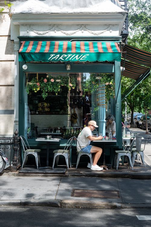 Free A man enjoying a sunny day at a charming café with outdoor seating. Stock Photo