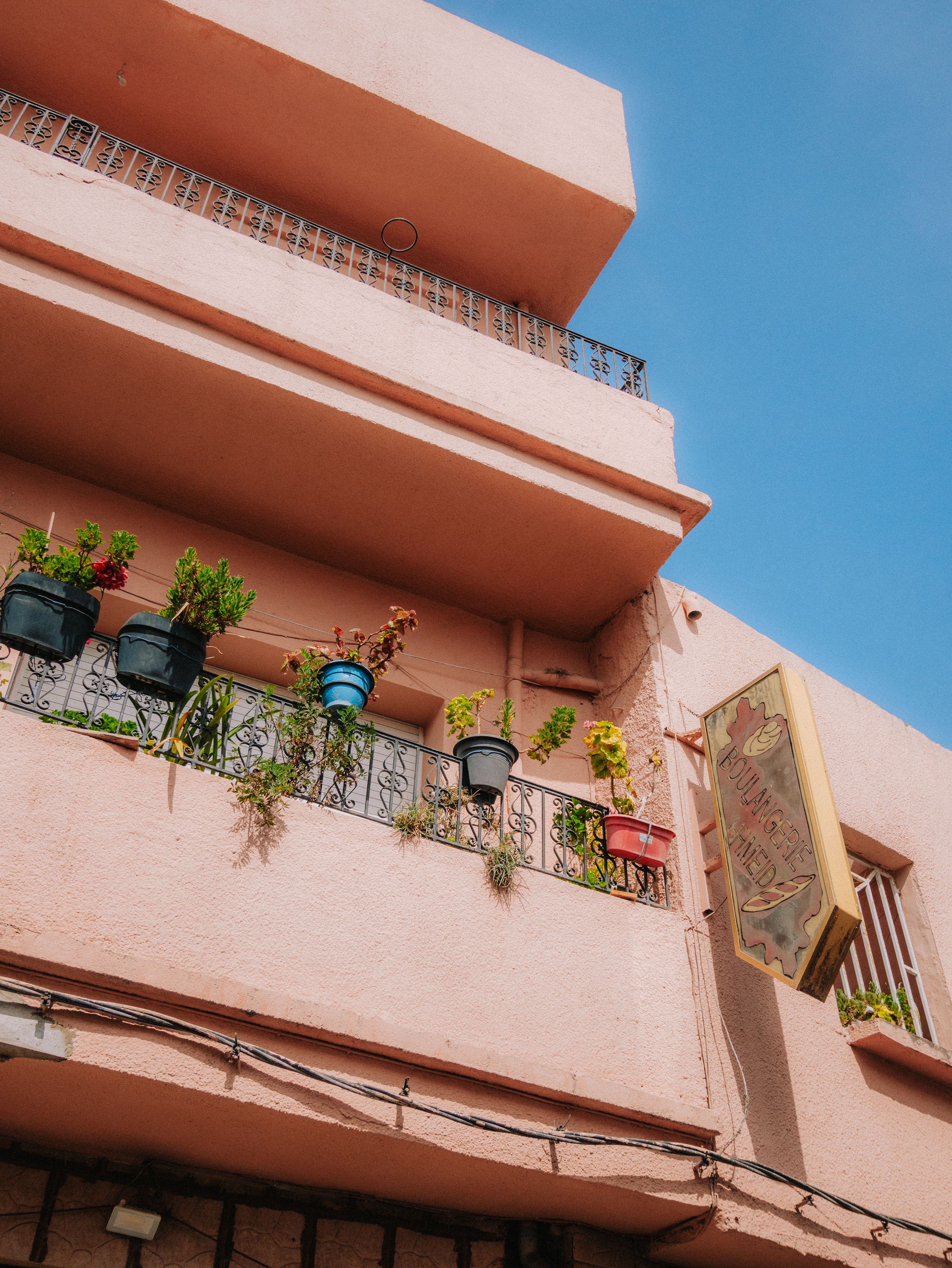 A pink building with plants on the balcony · Free Stock Photo