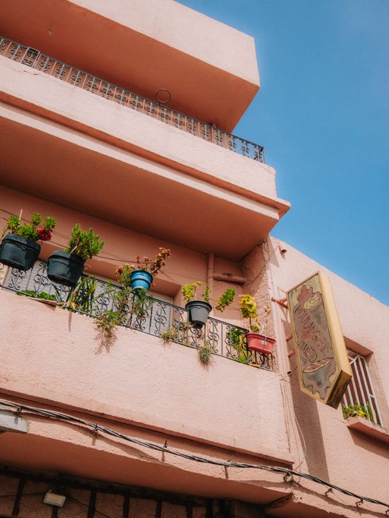 A pink building with plants on the balcony · Free Stock Photo