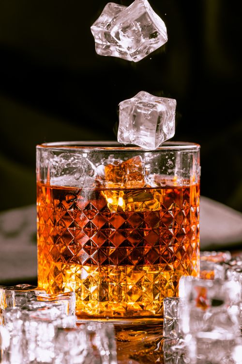 Free Capture of whisky in a crystal glass with ice cubes in motion. Perfect for luxury and refreshment concepts. Stock Photo