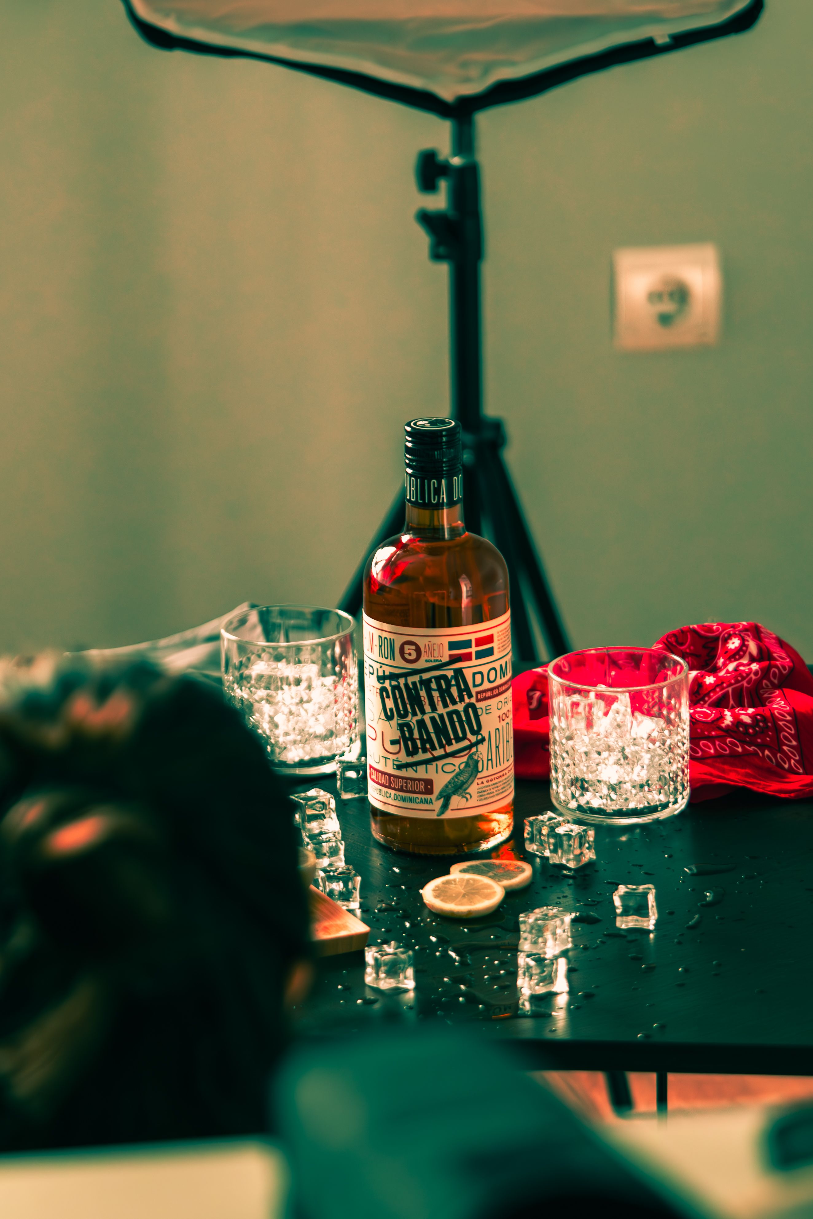 Warm indoor setting featuring a drink bottle, glasses, and a red bandana on a table.