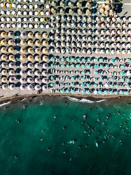 A vibrant aerial shot of Velipojë Beach, Albania, featuring colorful umbrellas and turquoise waters.