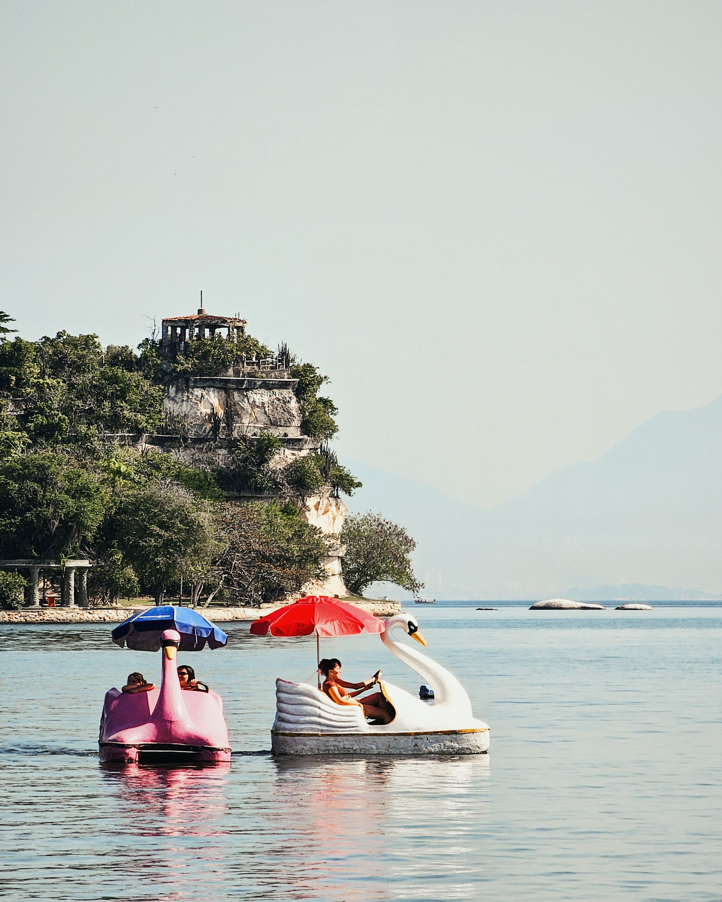 Bird-Shaped Pedal Boats on Sea Shore in front of Ruins atop Cliff ...