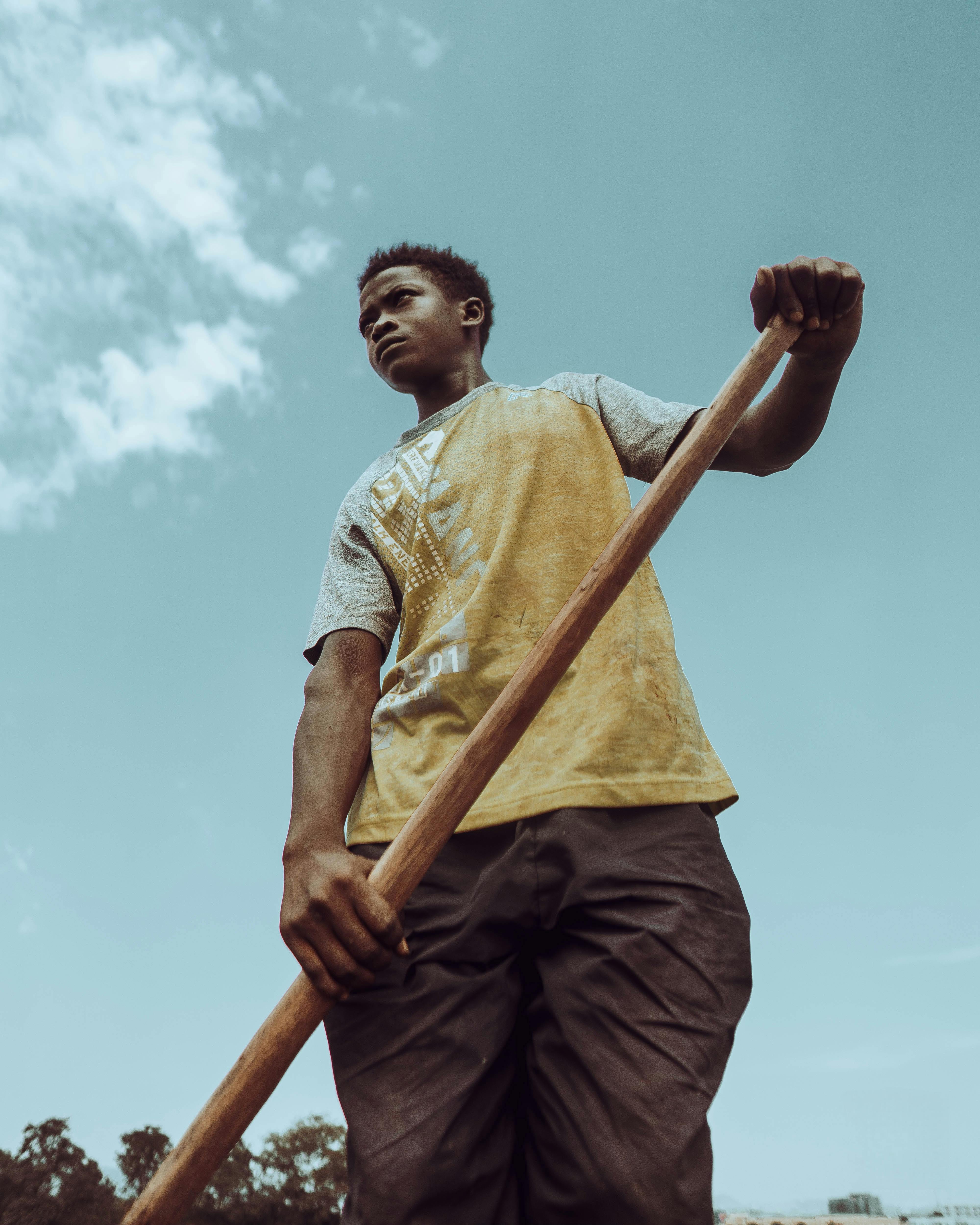 a young man holding a wooden stick in the air