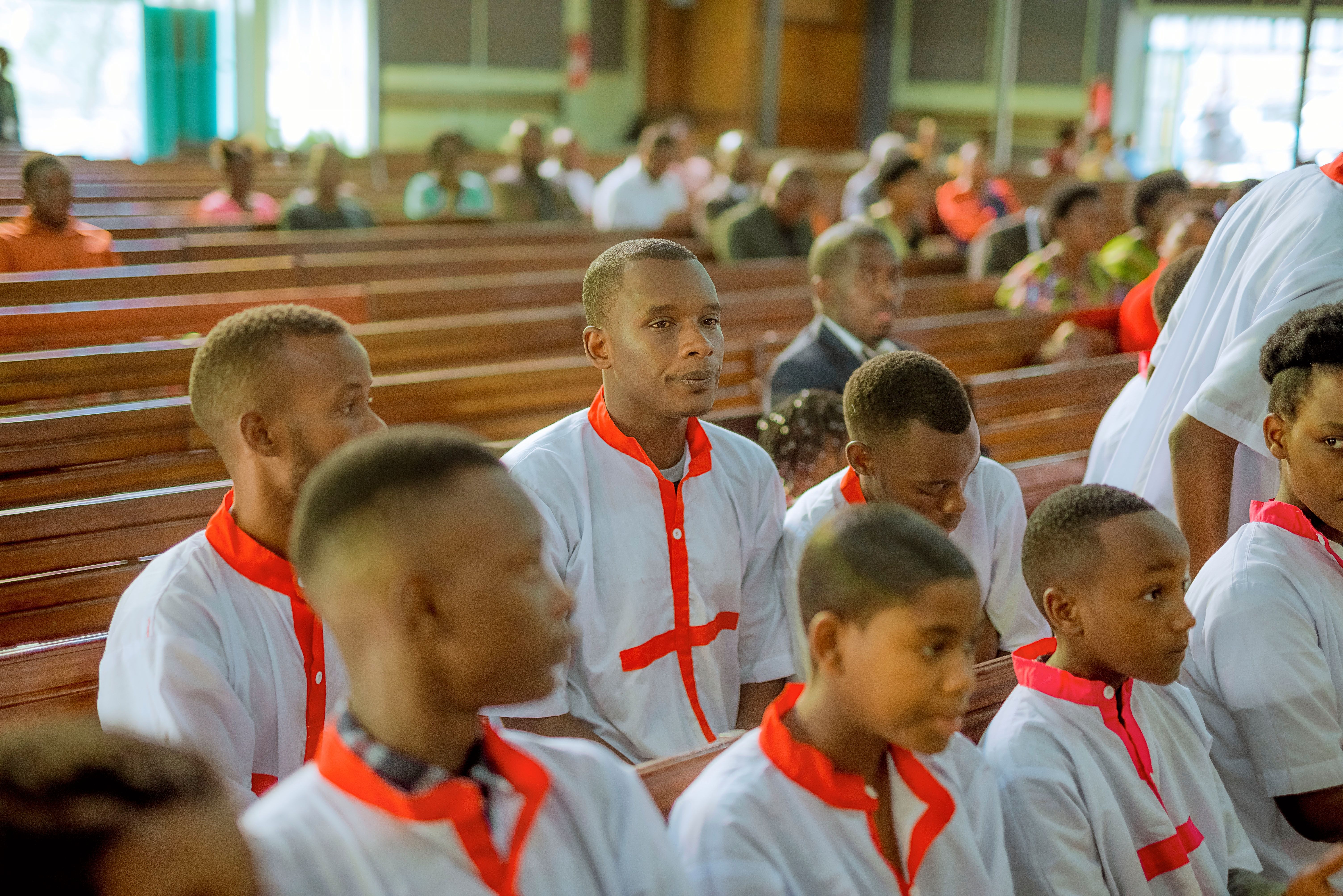 A group of young men in white and red robes sitting in pews · Free ...