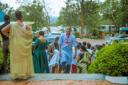 A group of adults in traditional attire at an outdoor religious ceremony with lush greenery.