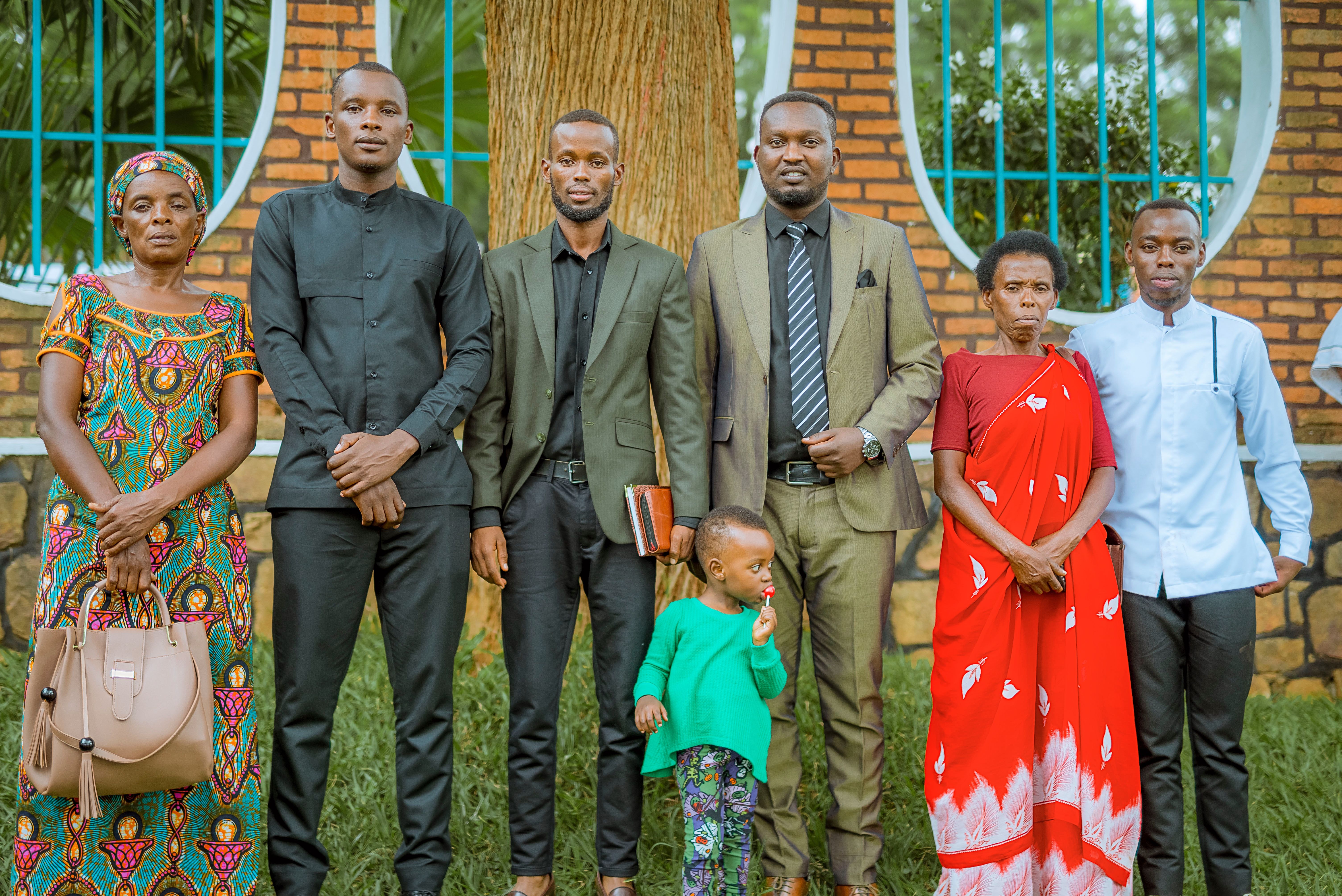 A diverse family poses together outdoors, showcasing cultural attire and joyful expressions.