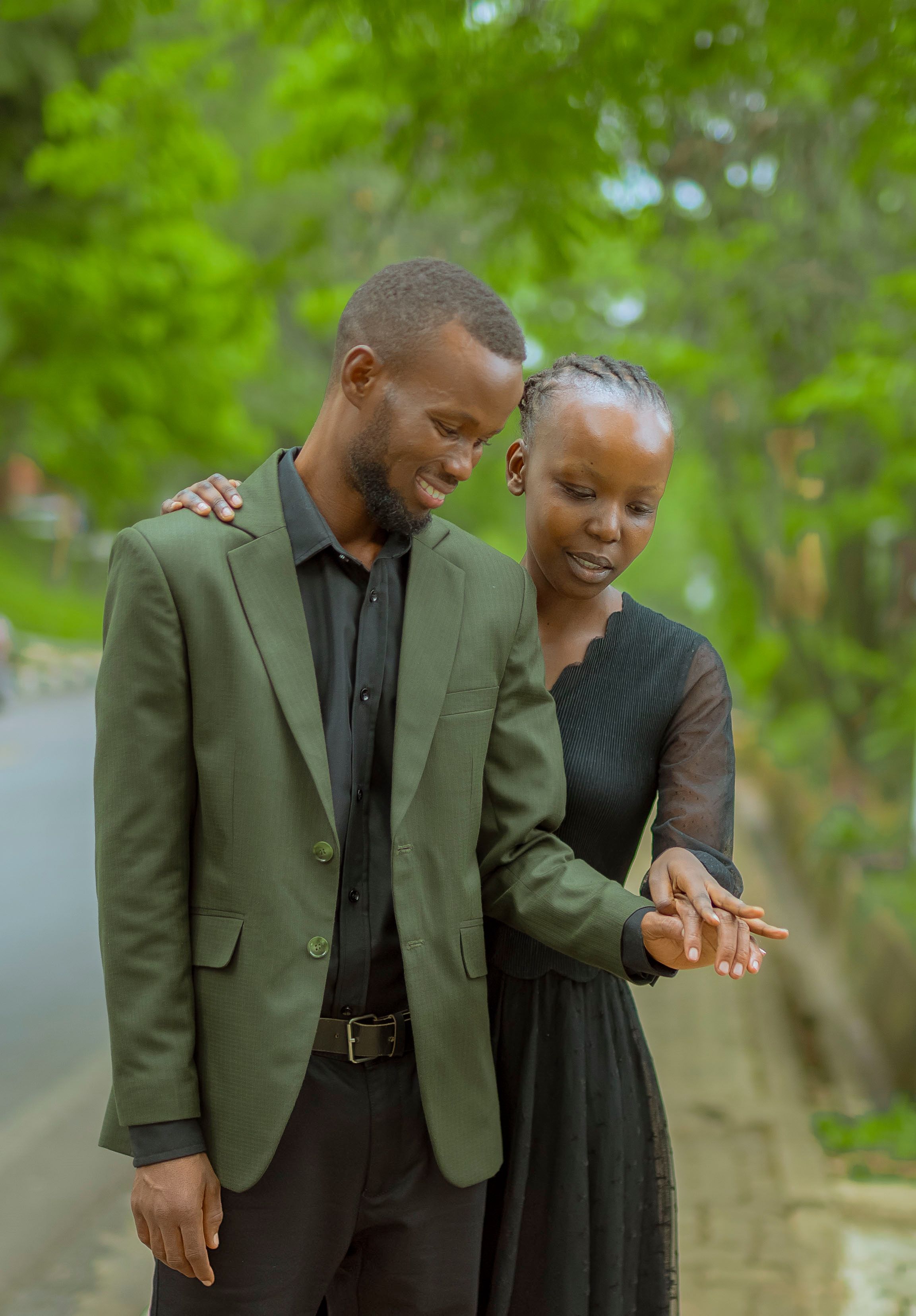 Happy couple sharing a romantic moment, showing engagement ring outdoors.