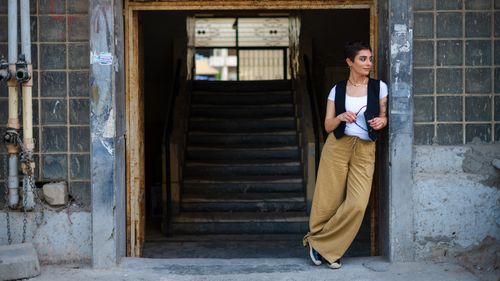 Free Stylish woman standing at a vintage building entrance, exuding urban charm and elegance. Stock Photo