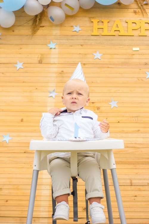 Cute Baby Sitting on a High Chair Celebrating His Birthday