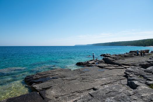 Beautiful rocky shoreline of Georgian Bay, Ontario, with clear turquoise waters and bright blue sky.