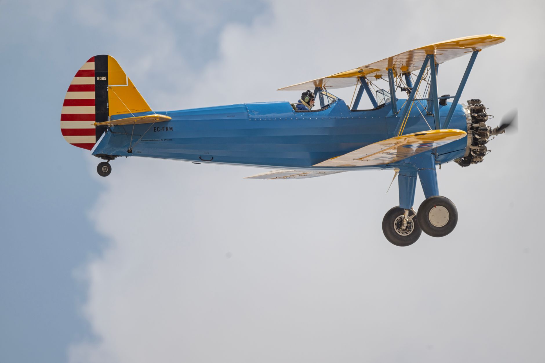 A vintage blue biplane performing aerobatics in the sunny skies of Madrid. Captured in stunning detail.