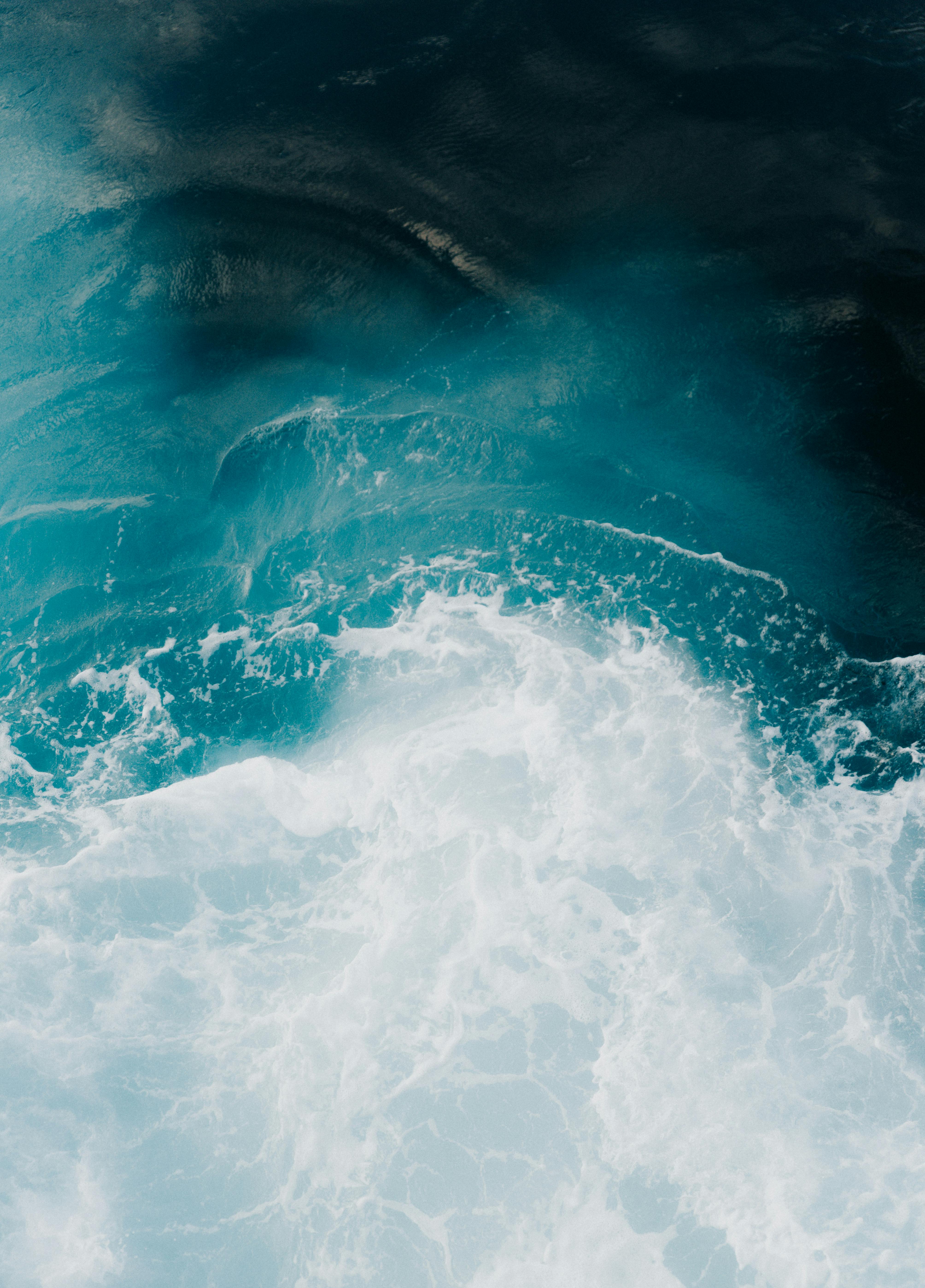 Captivating aerial view of the ocean's turquoise waves crashing with contrasting foam.