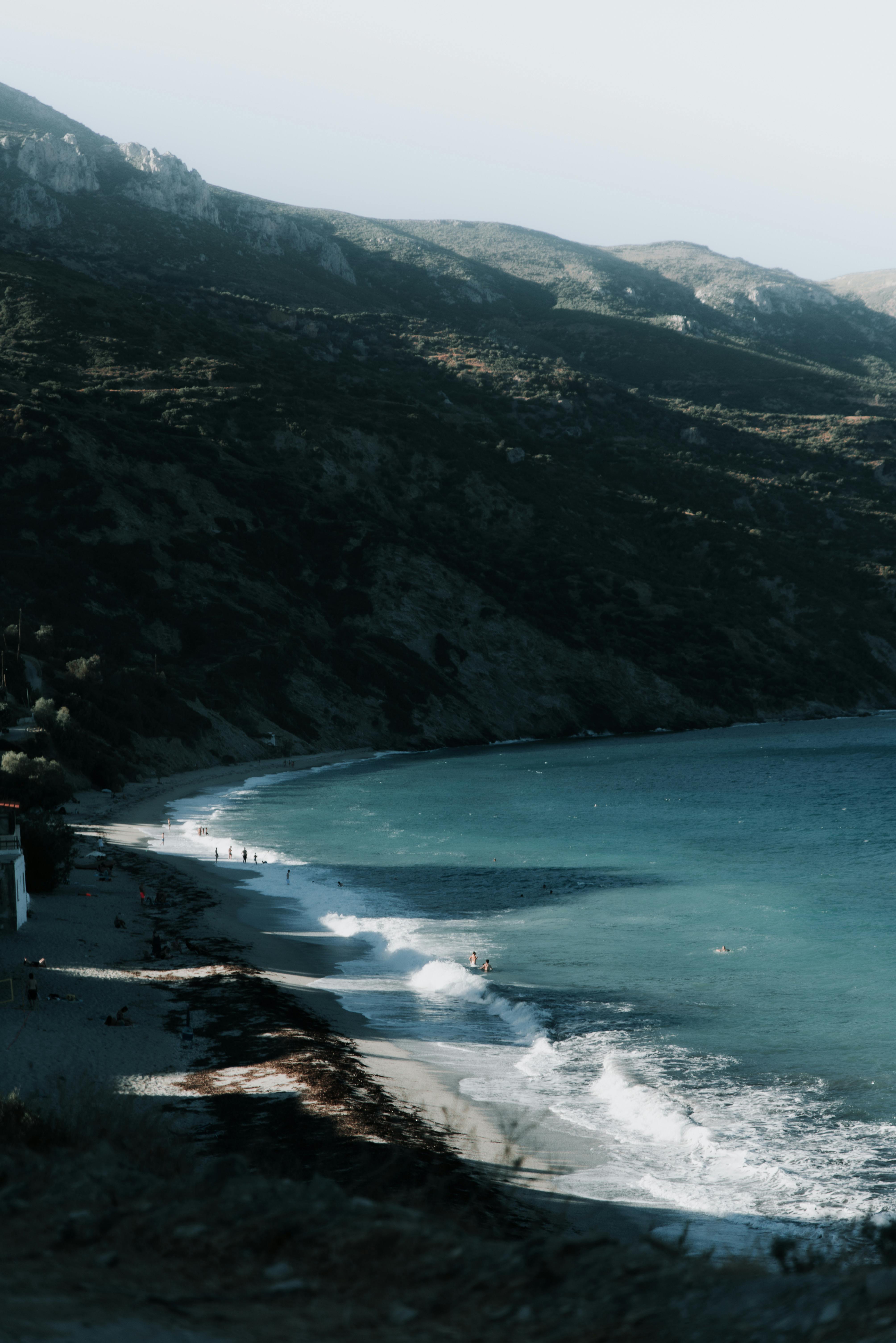 Breathtaking view of a coastal landscape featuring blue sea, sandy beach, and lush mountains.