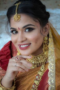 Portrait of a beautiful Indian bride adorned with gold jewelry and traditional attire, showcasing elegance and cultural richness.