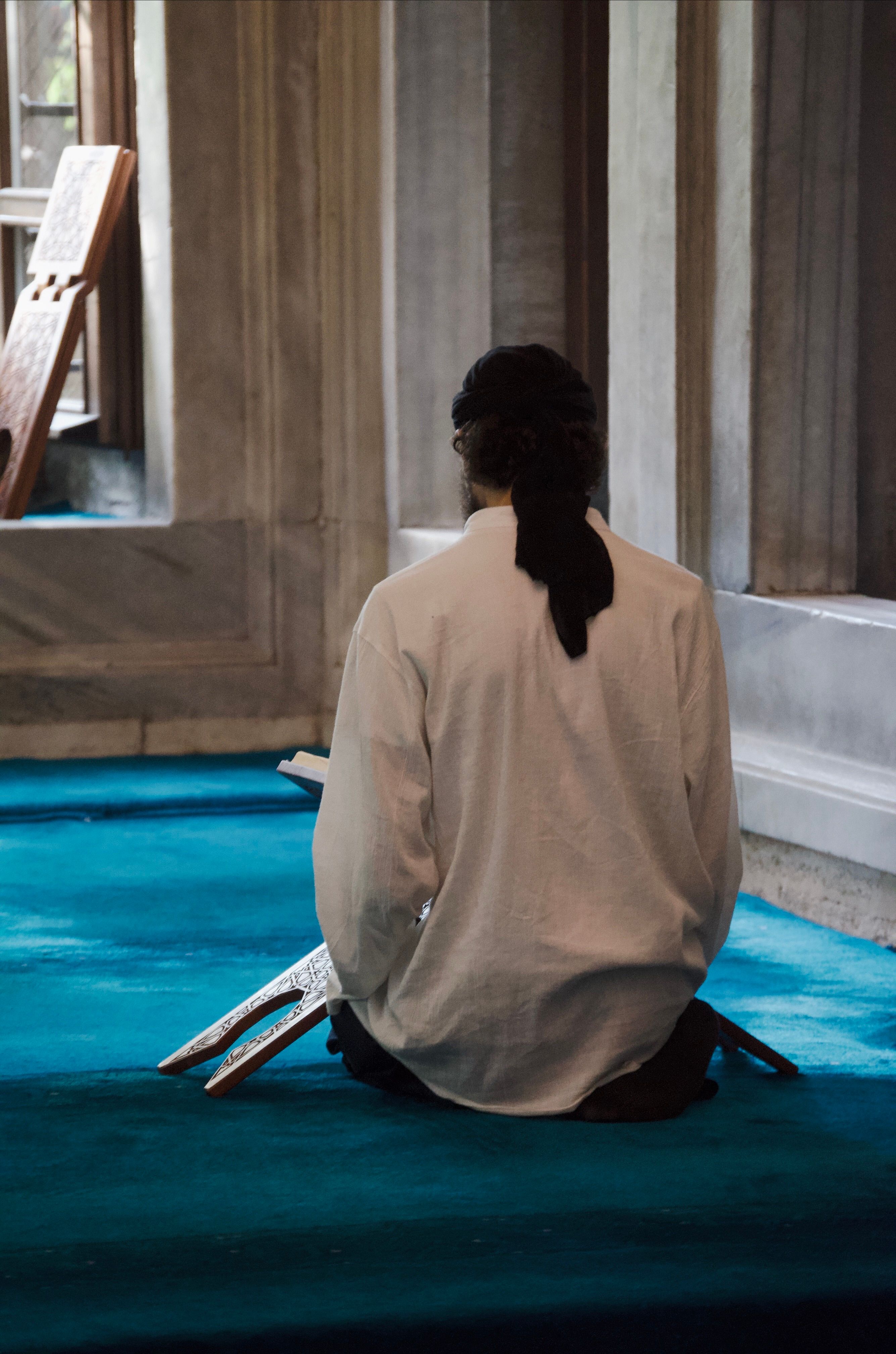 A man sitting in prayer inside a mosque in Istanbul, Türkiye, reflecting a serene spiritual moment.
