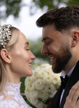 Close-up of a joyful bride and groom sharing a romantic moment on their wedding day outdoors.