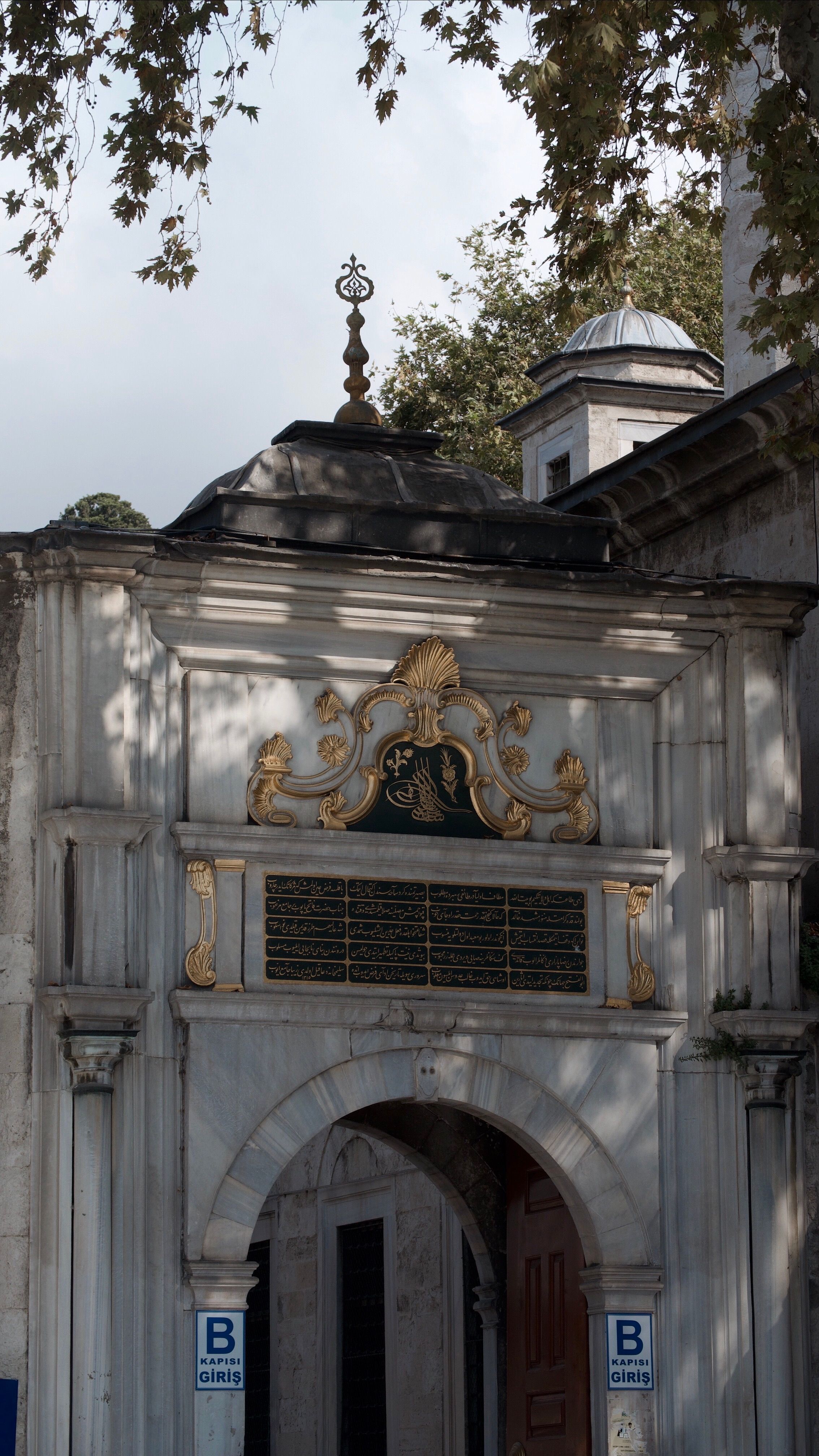 A beautifully carved historic archway with intricate gold details in an outdoor setting.