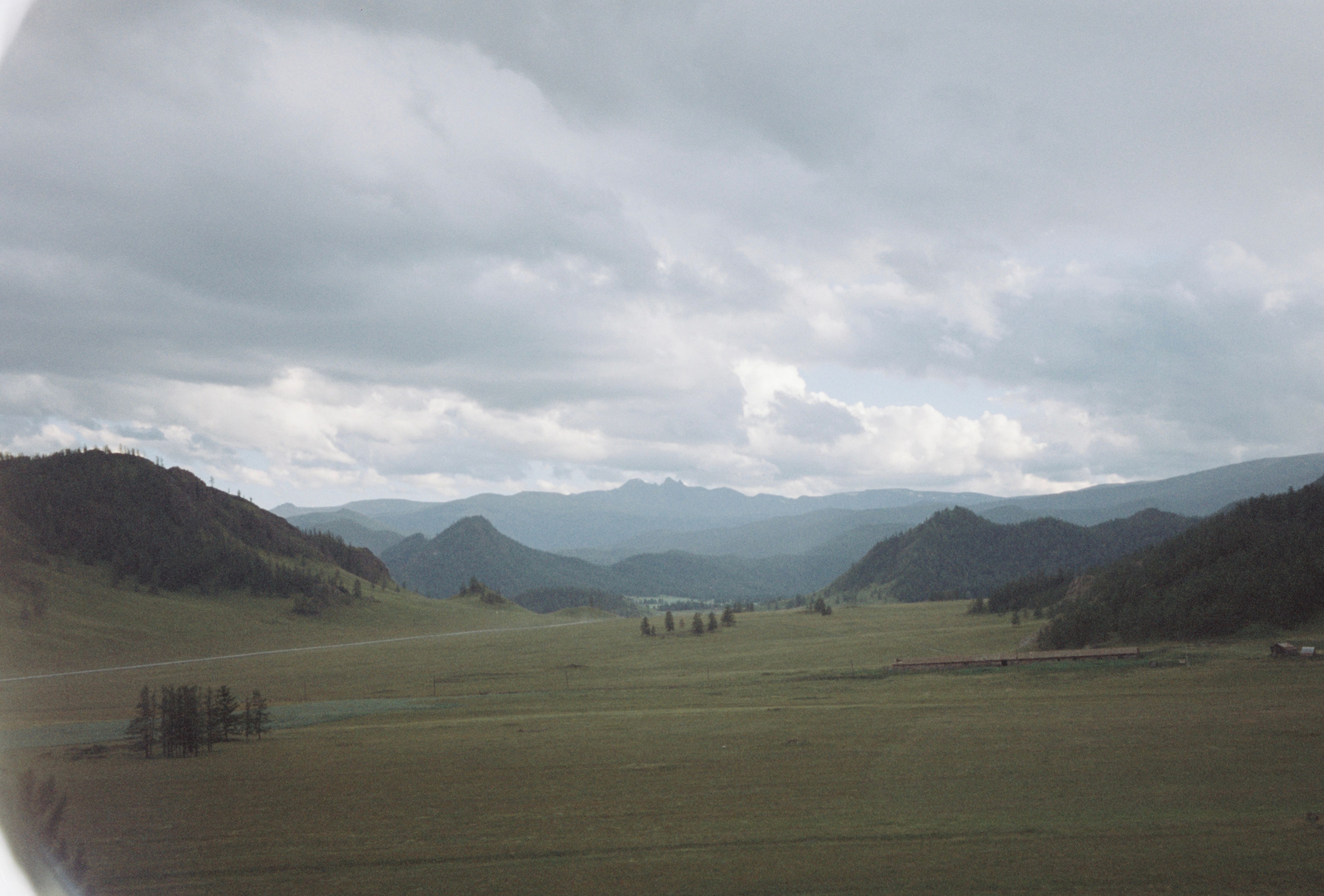 A view of a grassy field with mountains in the distance · Free Stock Photo