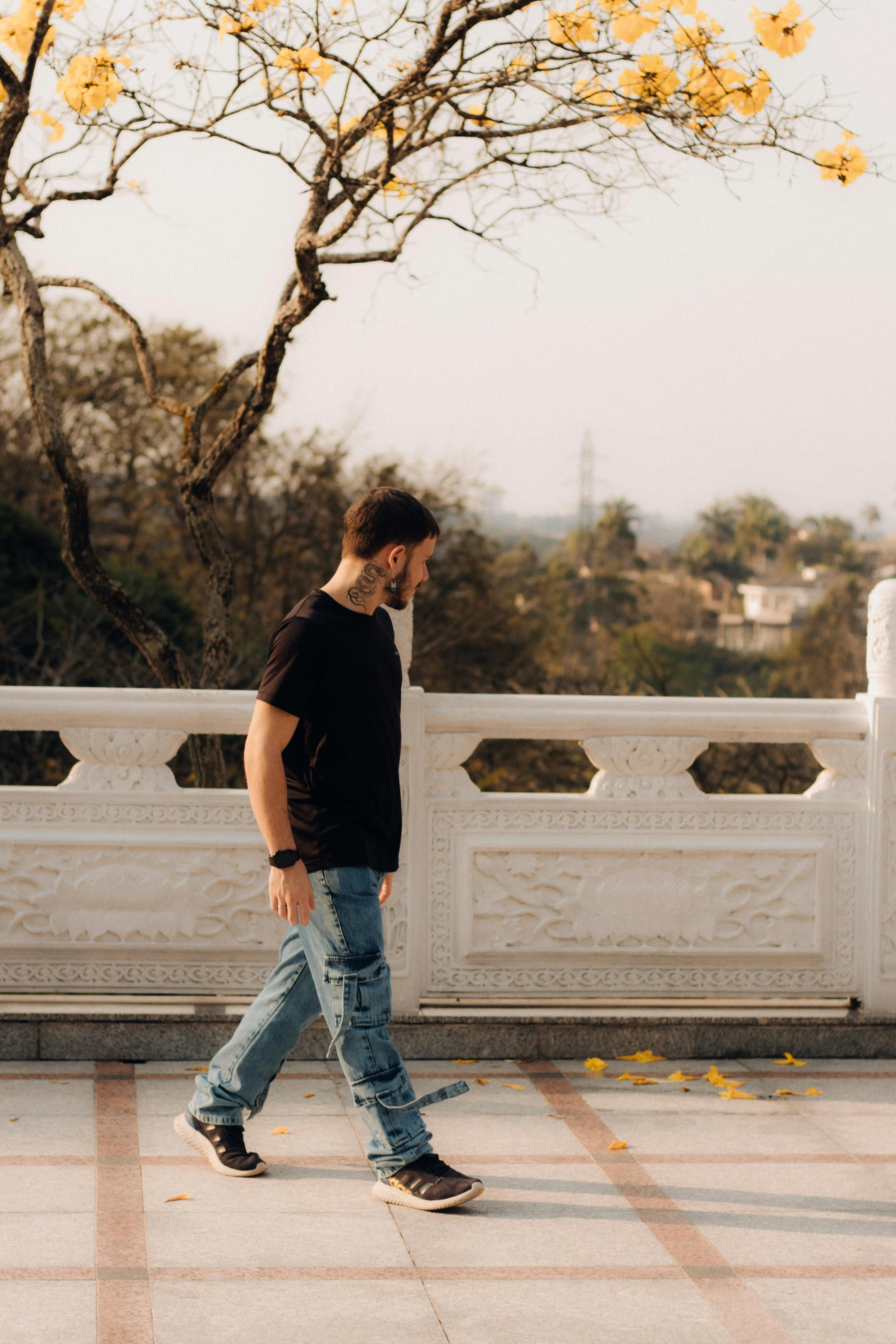 a man walking down a path with yellow flowers