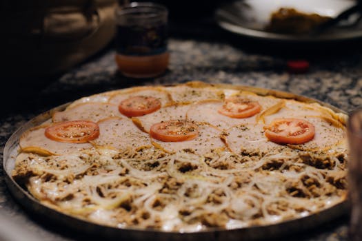 Freshly baked pizza topped with cheese, tomato slices, and onions, ready to be served.