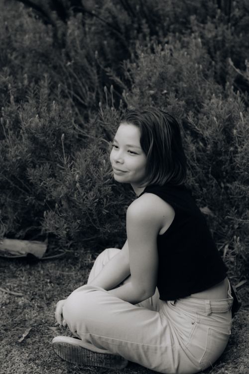 Free Black and white portrait of a teenage girl sitting thoughtfully in nature. Stock Photo