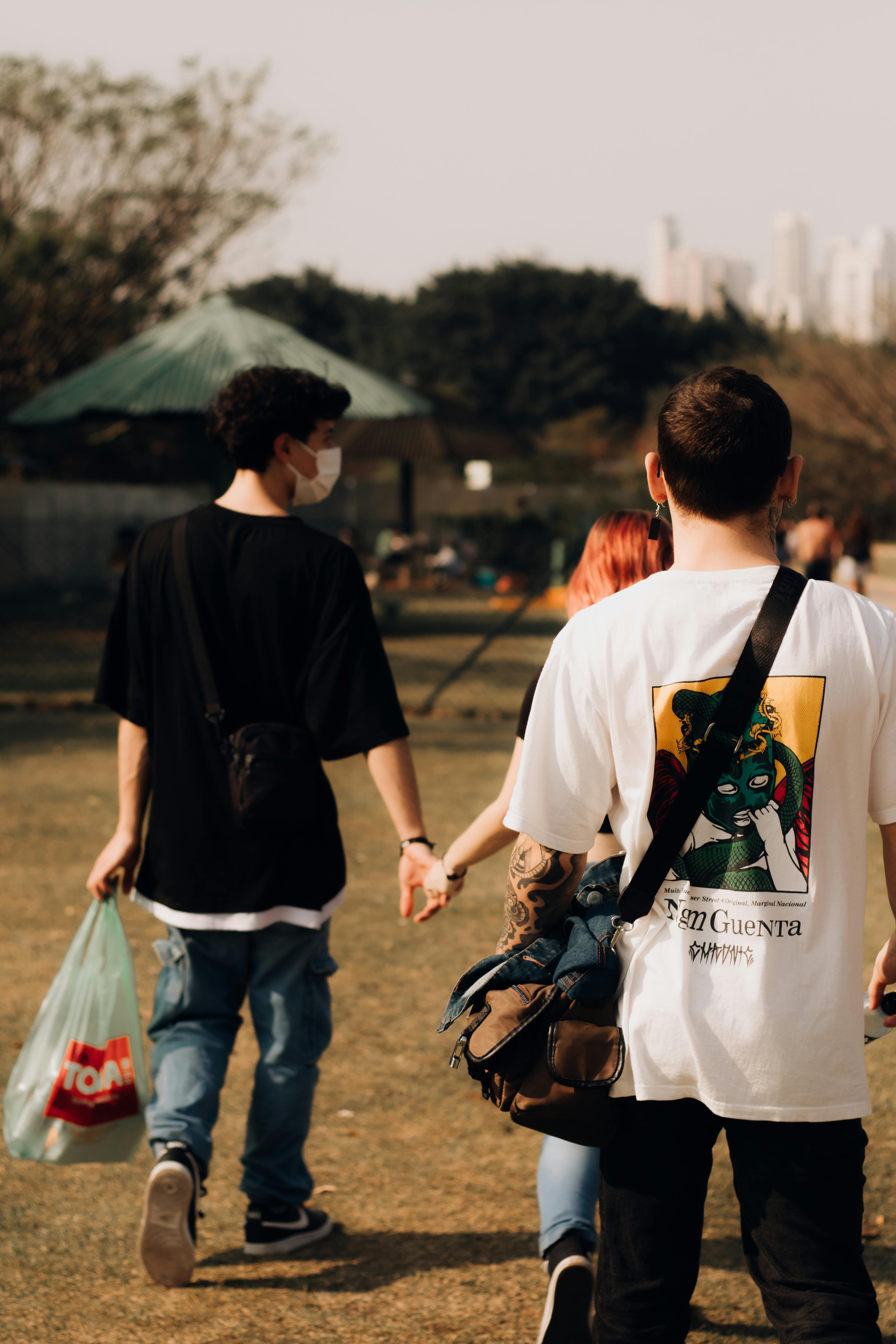 two people holding hands walking through a park