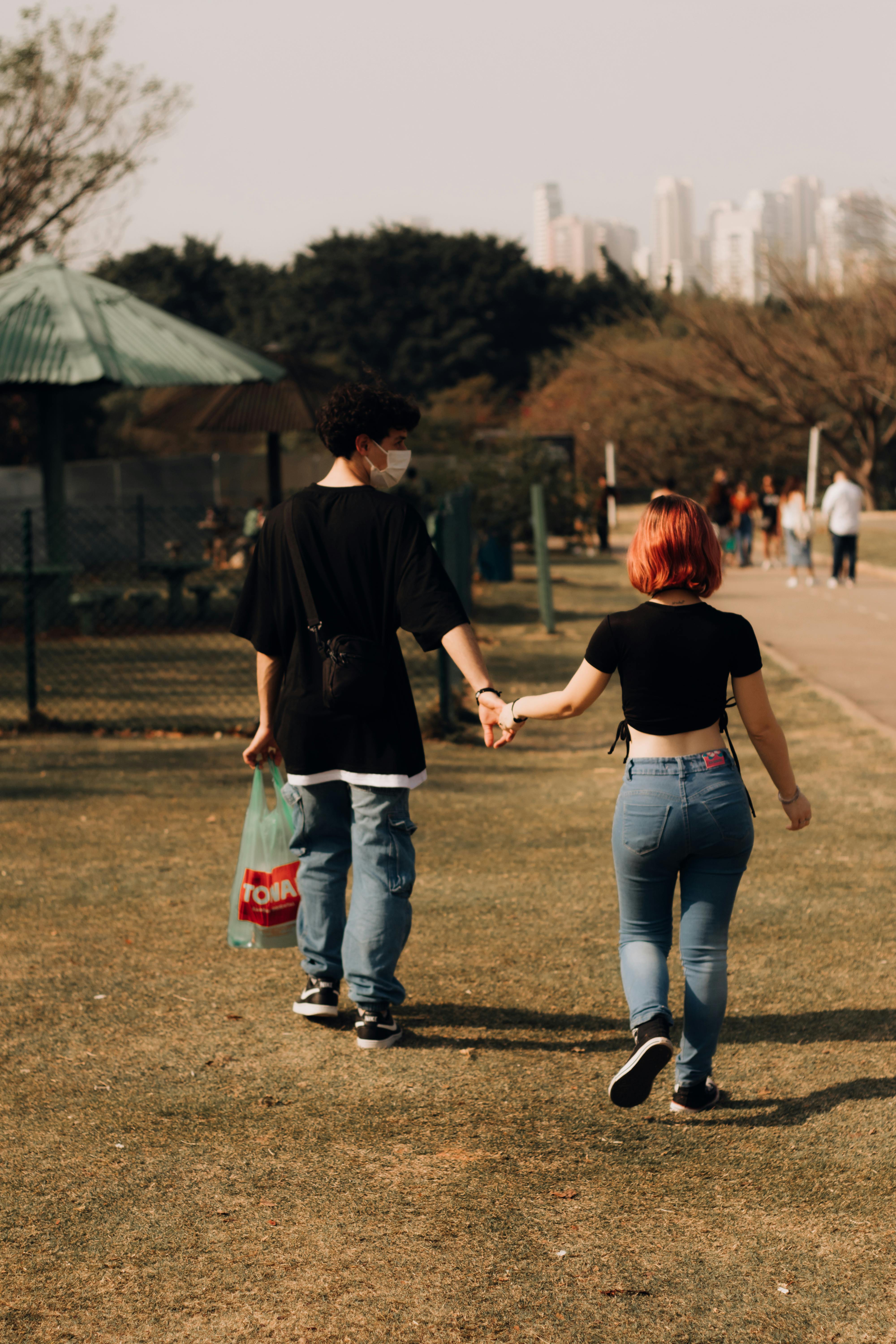 a couple holding hands walking through a park