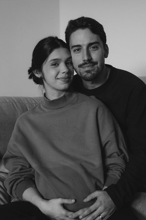 Free A monochrome portrait of a couple happily embracing, expecting a child, indoors. Stock Photo