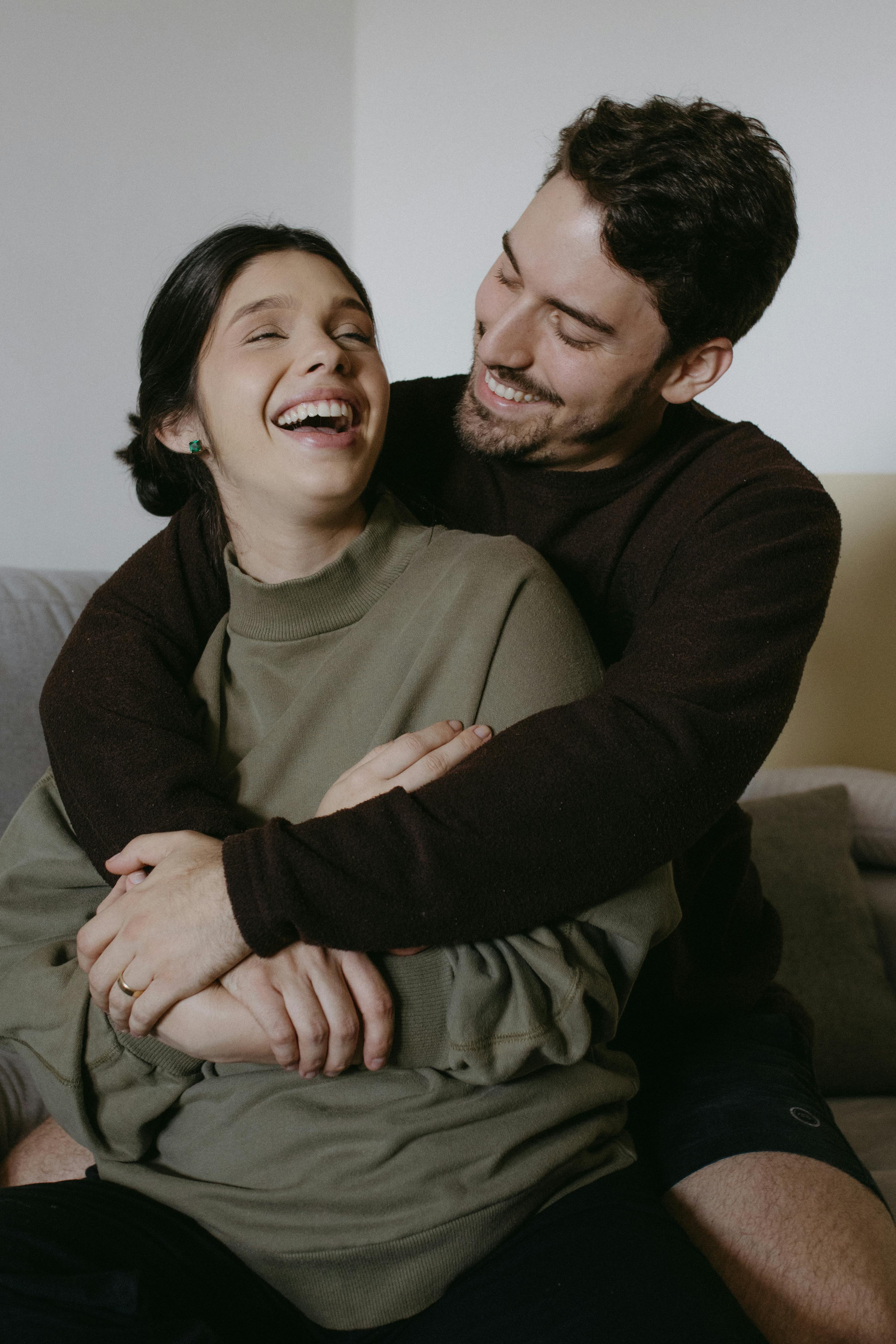 A man and woman laughing on a couch