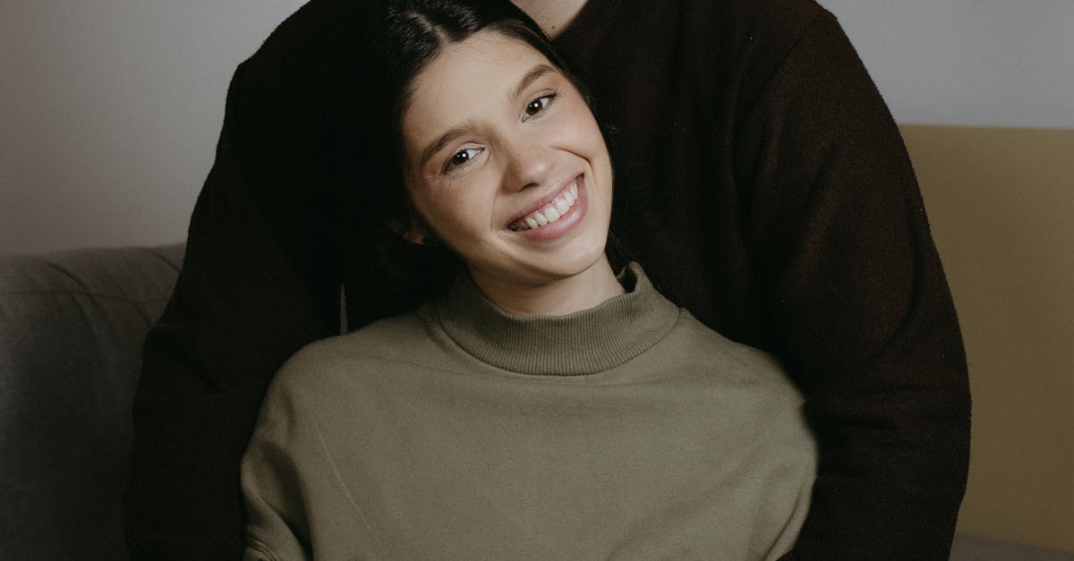A woman smiling while holding a bouquet of flowers in a sunlit room.