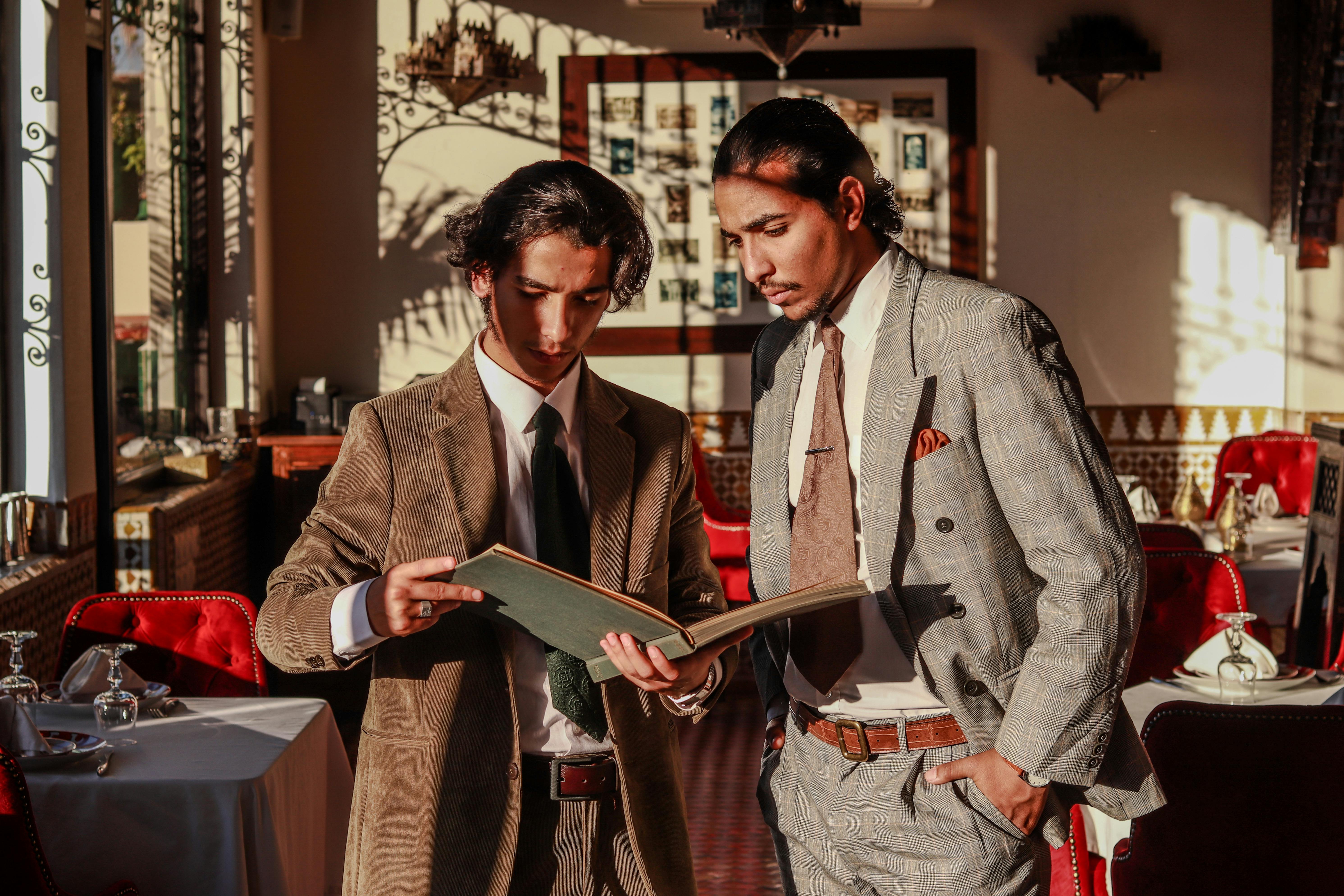 two men in suits looking at a menu