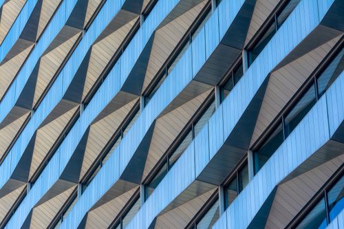 Free Detailed view of a modern skyscraper's geometric facade with glass elements. Stock Photo