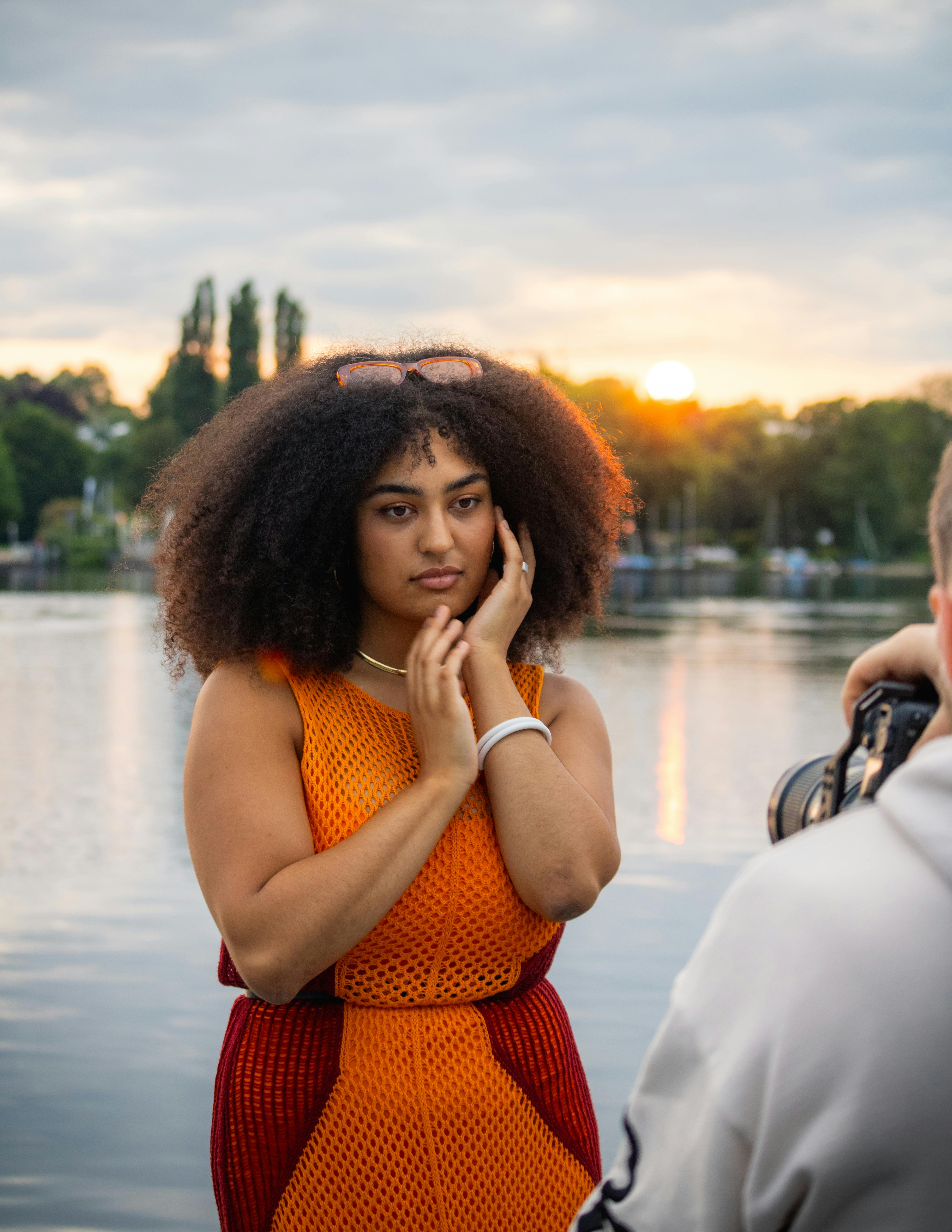 a woman in an orange dress is taking a photo of a man