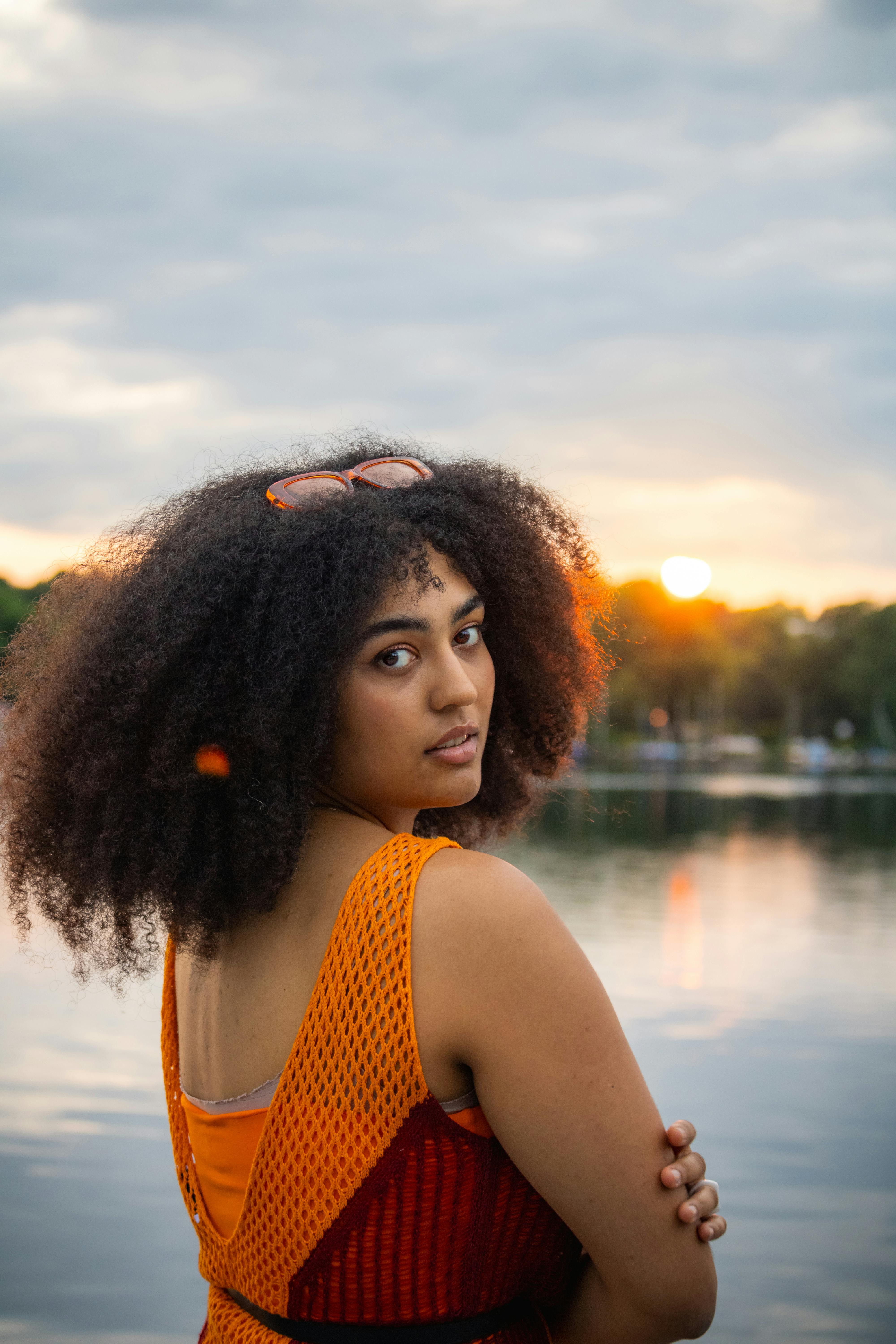 a woman with afro hair standing in front of a lake