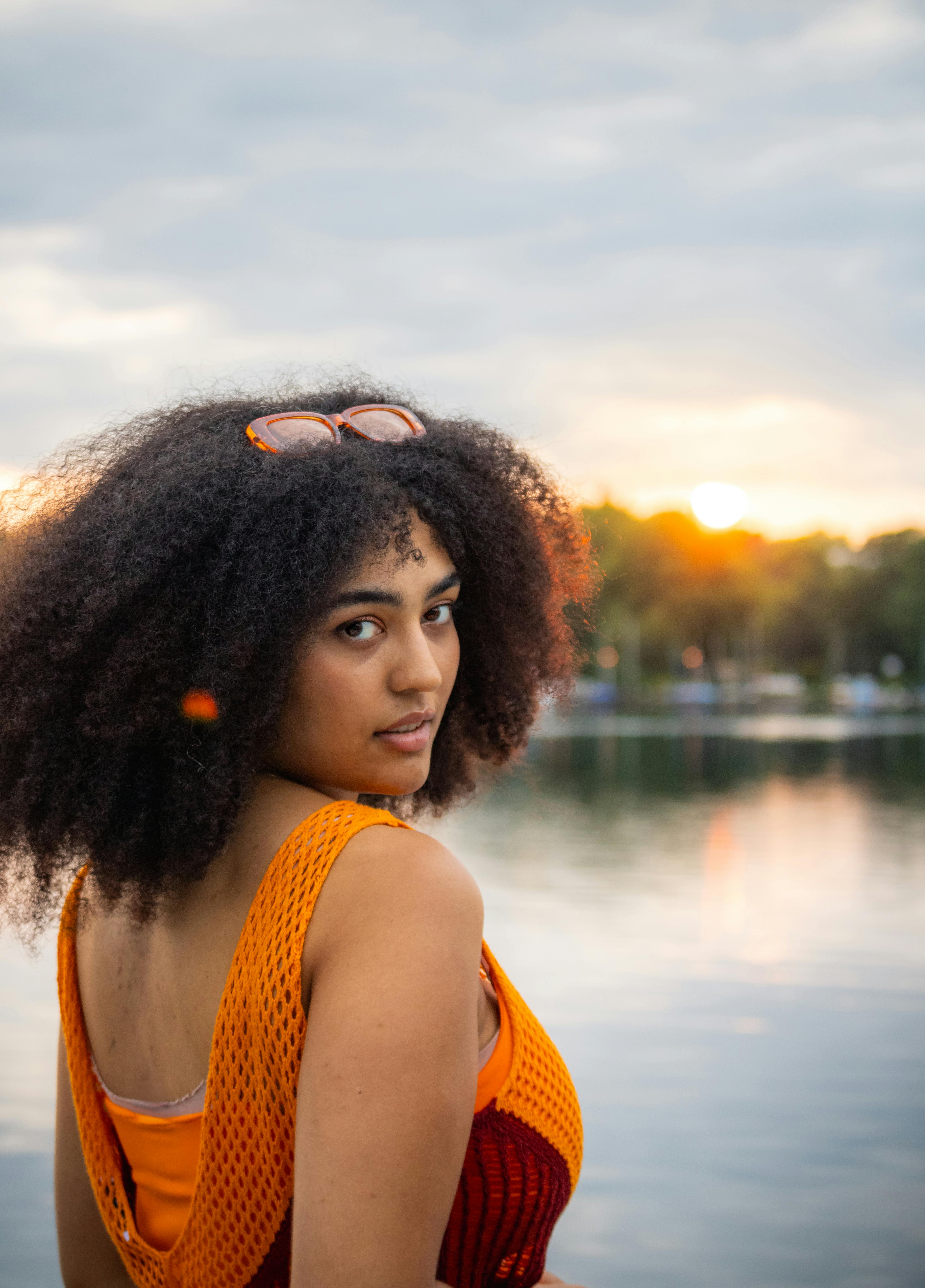 a woman with an afro wearing an orange dress and sunglasses