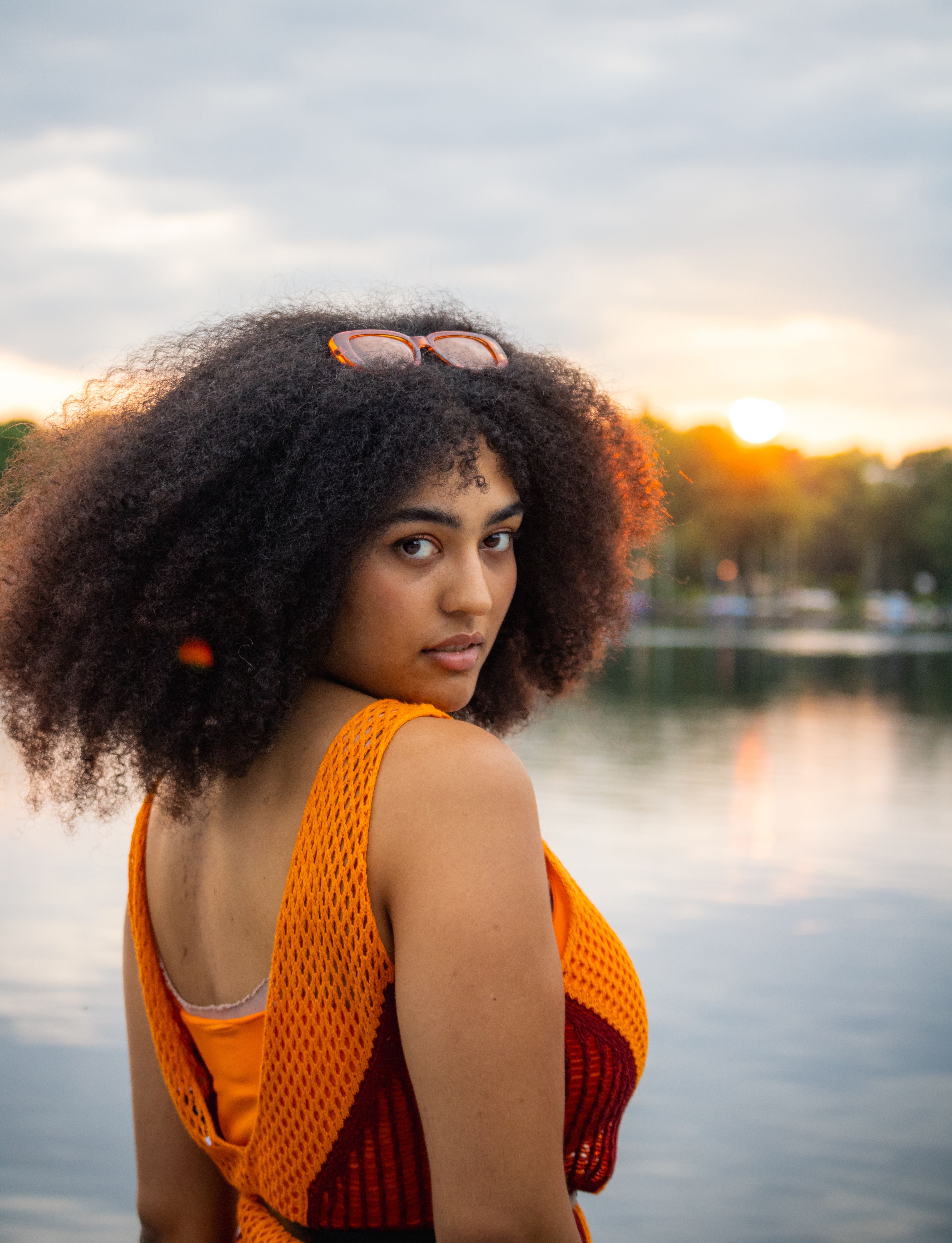 A woman with afro hair standing in front of a lake · Free Stock Photo